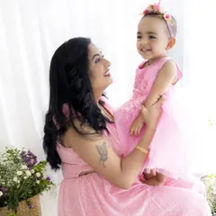 A beautiful, happy moment between a mother and her daughter during a Mother's Day mini-session. Both are dressed in matching pink, surrounded by flowers.