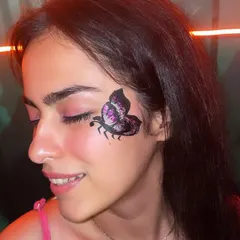 A delicate and detailed butterfly design painted on the cheek, with hints of purple glitter for a touch of sparkle.