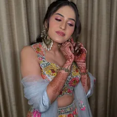 Showing off her beautiful mehendi design. The soft pink makeup complements the intricate henna and the vibrant colors of her outfit.