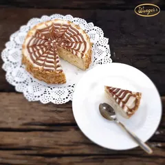 A slice of our classic Butterscotch Cake, served on a delicate doily. This cake has a light, nutty flavour, with crunchy butterscotch nougat mixed into the cream and a beautiful web-like pattern on top.