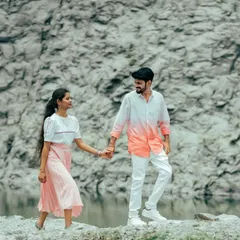 A couple walks hand-in-hand along the edge of a quarry lake. Their casual outfits and the rugged landscape create a beautiful contrast.