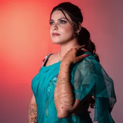 A stunning bridal portrait of Priya, using colored lighting to create a dramatic, editorial feel. This highlights her makeup, hairstyle, and the rich color of her saree.