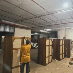 An artisan in my workshop applying the final coat of polish to a batch of these custom wardrobes.