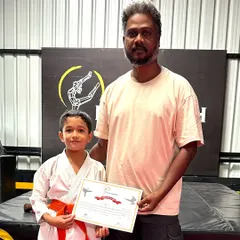 This student proudly holds his new orange belt and certificate. Our belt exams are a formal recognition of the skills and discipline our students develop in their karate training.