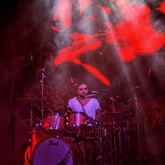 The intensity of a drummer, bathed in the fiery red of the stage. My goal is to capture the power and rhythm that drives the entire performance.