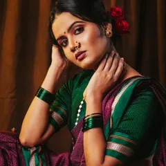 A powerful and emotive portrait of a model in a traditional Nauvari saree. The lighting is focused to create a painterly, classic feel against the rich brown backdrop.