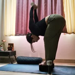 Using dumbbells to deepen a standing forward fold (Uttanasana). Incorporating light weights can help increase flexibility and build strength in the shoulders and back, showing how props can evolve your practice.