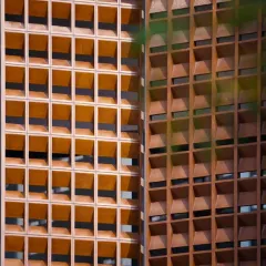 A close-up of the 'dancing screens' on the House of Dancing Screens. These pivoting terracotta blocks are precisely crafted to create a fluid, rhythmic pattern that allows the façade to respond to the elements and the family's need for privacy.
