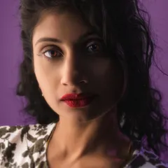 A close-up from a studio session where I experimented with lighting and a bold purple background. I focus on retouching the mood and colors to make the portrait pop, not change your face.