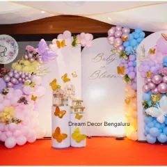 A 'Baby in Bloom' baby shower with a butterfly theme. The pastel balloon arrangements in pink, purple, and blue create a soft and dreamy atmosphere.
