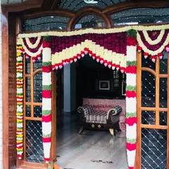 A classic housewarming door decoration with garlands of velvet-red, white, and green flowers. This traditional design is perfect for welcoming guests into your new home.