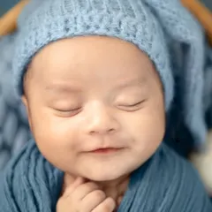 A close-up portrait of a newborn's sweet, smiling face while they dream. Capturing these fleeting expressions is what makes newborn photography so special.