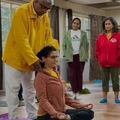 I am adjusting a student's neck and shoulder alignment to ensure her spine is perfectly straight for pranayama practice.