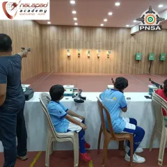 A family enjoying a session together. An adult practices with an air pistol while young shooters take aim with rifles. It's a wonderful activity that brings different generations together.