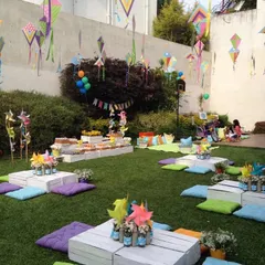 A low-seating picnic arrangement with colorful cushions and hanging kites. This setup is perfect for a casual and fun outdoor gathering.