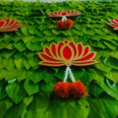 A close-up of the betel leaf wall, showing the detail of the leaves and the hanging lotus motif with a small marigold tassel.