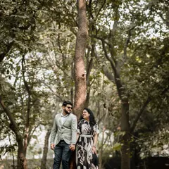 A wide shot of the couple in a serene forest setting. The tall trees create a beautiful, natural frame, emphasizing the feeling of being in their own private world.