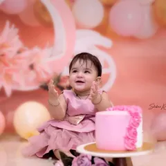 The moment of anticipation right before the cake smash begins. This little girl is all smiles, surrounded by a beautiful pink and gold setup for her first birthday.