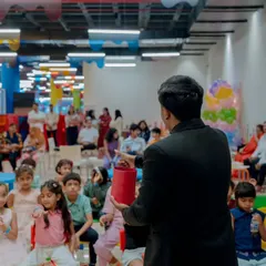 A view from behind me as I perform for a full house at a kids' play zone. The audience includes both children and their parents, as my show is designed for the whole family to enjoy together.