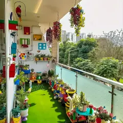 A playful and colorful balcony garden designed for a family. The space is filled with whimsical, brightly painted planters and birdhouses, creating a fun outdoor activity area.