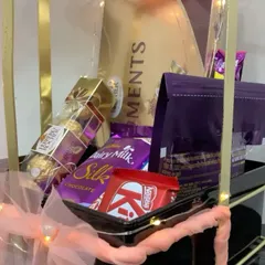 Another view of the chocolate-filled metal bow hamper, highlighting the layers of different treats like Ferrero Rocher, Dairy Milk Silk, and KitKat.