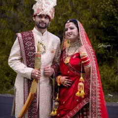 A classic wedding portrait of a Himachali couple. The groom holds a traditional sword while the bride smiles, perfectly capturing the blend of tradition and happiness.