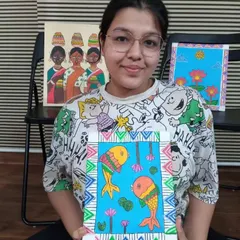 Adhya, an 11th standard student, holding her Madhubani painting of fish. This traditional art form uses bold lines, patterns, and bright acrylic colors on canvas.