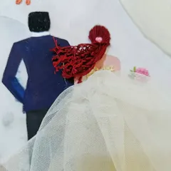 A detailed view of the Western wedding hoop, focusing on the bride's red hair made of thread and the flowing tulle veil.
