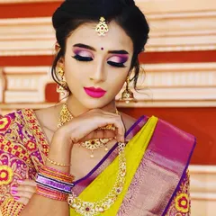 A close-up on the details of a dramatic bridal look. The vibrant pink and purple eyeshadow is blended to create a bold statement, perfectly matching the bride's colorful saree and enhancing the overall festive feel.