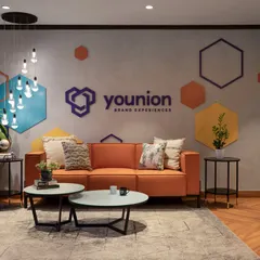 The reception waiting area is brought to life with a bright orange sofa and colorful geometric graphics on the wall, immediately communicating the company's energetic and creative brand identity.