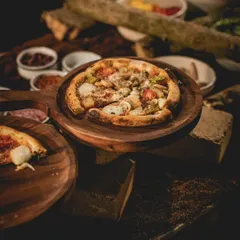 A gourmet vegetarian pizza is presented on a rustic wooden platter. Topped with artisanal cheese and fresh vegetables, our sourdough pizzas are a highlight of our global cuisine offerings.