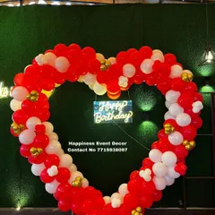 A large, heart-shaped balloon arch is a bold and romantic statement piece. I built this one with red and white balloons against a green wall, complete with a neon sign, perfect for anniversaries or proposals.