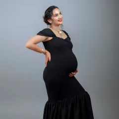 A classic and powerful portrait in a black mermaid gown. The simple grey backdrop makes the mother-to-be's joyful expression and beautiful form the center of attention.