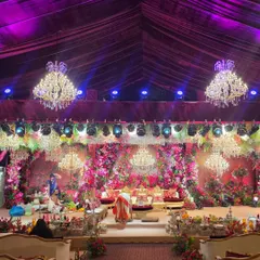 A full view of the grand floral wedding stage and the guest seating area. The purple uplighting and extensive floral work create a cohesive and luxurious ambiance throughout the venue.
