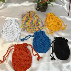 A vibrant collection of my handmade crochet potli bags. These drawstring pouches come in many colors, including solid white, blue, black, red, yellow, and a fun rainbow yarn, making them perfect for any occasion.