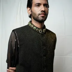 A close-up portrait that draws attention to the jeweled collar of the vest. The lighting is carefully controlled to highlight the texture of the fabric and the model's strong features.