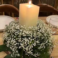 Ambiance is created through thoughtful details. This centerpiece, featuring a block candle nestled in a bed of baby's breath on a rustic wood slice, added a warm and romantic glow to each table.