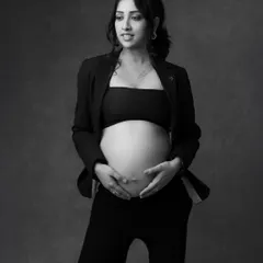 A chic and stylish solo maternity shot. The open blazer beautifully frames the baby bump, creating a bold and fashionable statement in black and white.
