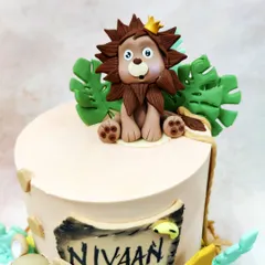 A close-up of the adorable crowned lion topper from our safari cake, surrounded by edible monstera leaves.