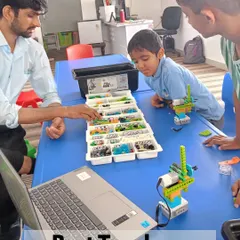 An instructor guides two young students as they work on a robotics project. This image highlights the personalized attention and expert guidance children receive in my classes, ensuring they understand the concepts behind what they are building.