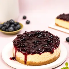 The glossy blueberry compote is the focus of this cheesecake shot. The slight drip down the side adds a delicious, tempting quality, while the bright background keeps the image looking fresh and modern.