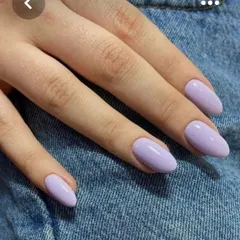 A beautiful solid color manicure in a trendy pastel lavender shade on medium-length almond nails.