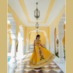 A vibrant bridal portrait in a sunlit palace corridor in Rajasthan. The bride's bright yellow lehenga and joyful twirl create a picture of pure happiness and celebration.