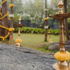 Creating a serene ambiance for an outdoor wedding ceremony. I placed traditional brass lamps on natural rock formations, decorated with marigold flowers to complement the rustic, natural setting.