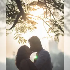 A romantic silhouette against the setting sun. This artistic shot uses backlighting to create a dreamy and timeless portrait of a couple's kiss.