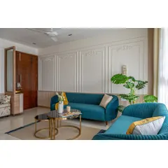 After: The same space transformed with elegant wall mouldings, a bold teal sofa, and sophisticated gold accents. This is the power of thoughtful design.