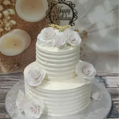 A pristine white two-tiered cake with delicate ridged buttercream and soft pink-tinted sugar roses. It’s a timeless design that brings a touch of class to any birthday.