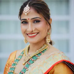 A classic South Indian look featuring a warm, glowing complexion and a traditional red bindi. The makeup is designed to harmonize with the beautiful green and gold tones of the pattu saree and temple jewelry.