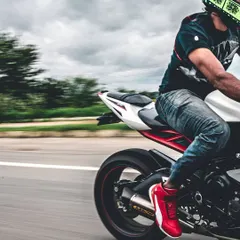 A panning shot from the rear, highlighting the rider's bright red shoes and the motion of the back wheel. This series captures the motorcycle from multiple dynamic angles.