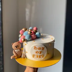 A simple and elegant "Boy or Girl" baby shower cake. This design features a cute teddy bear holding a string of pink, blue, and gold balloons.